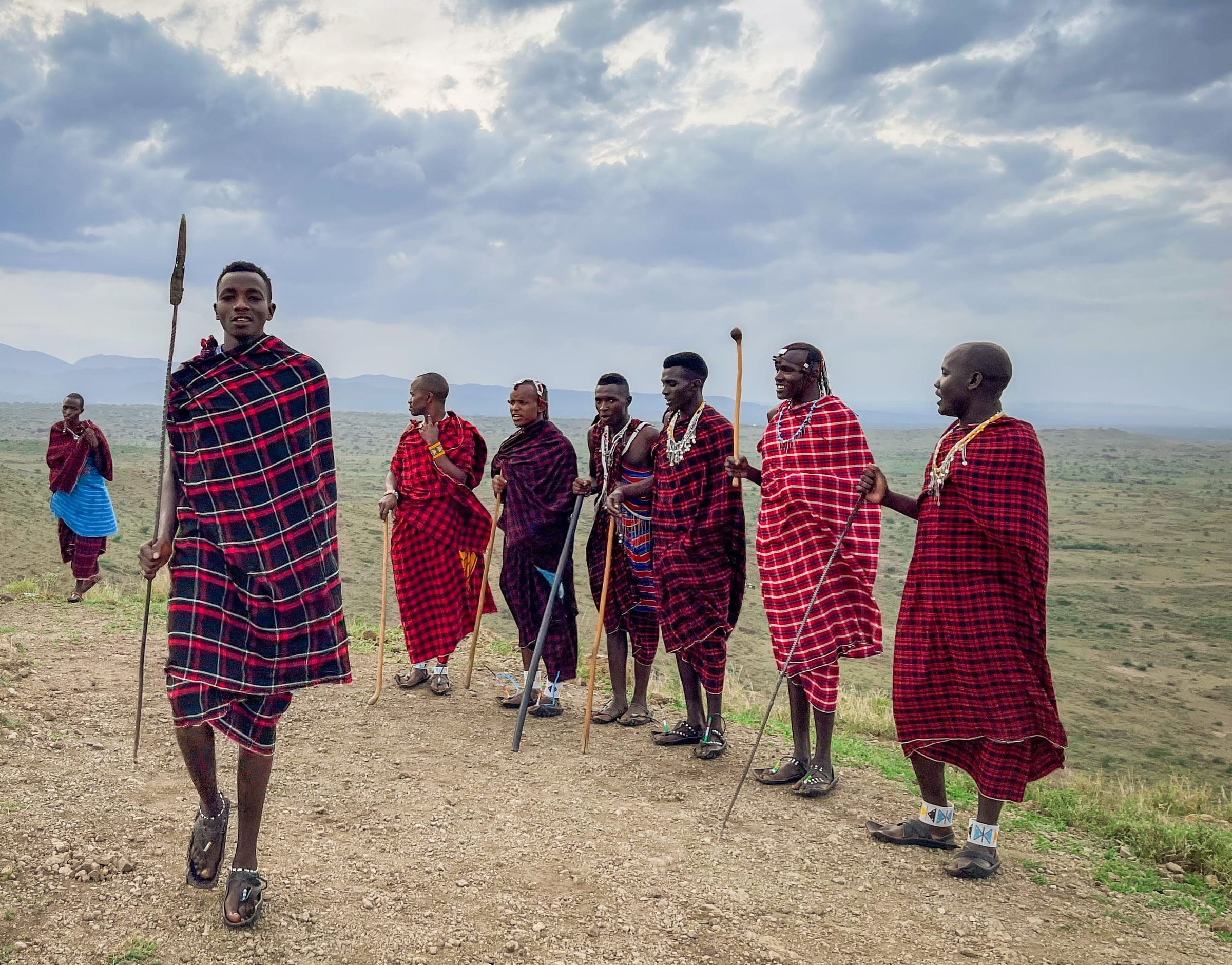 Young Maasai men in red shúkà on a ridge above open plains