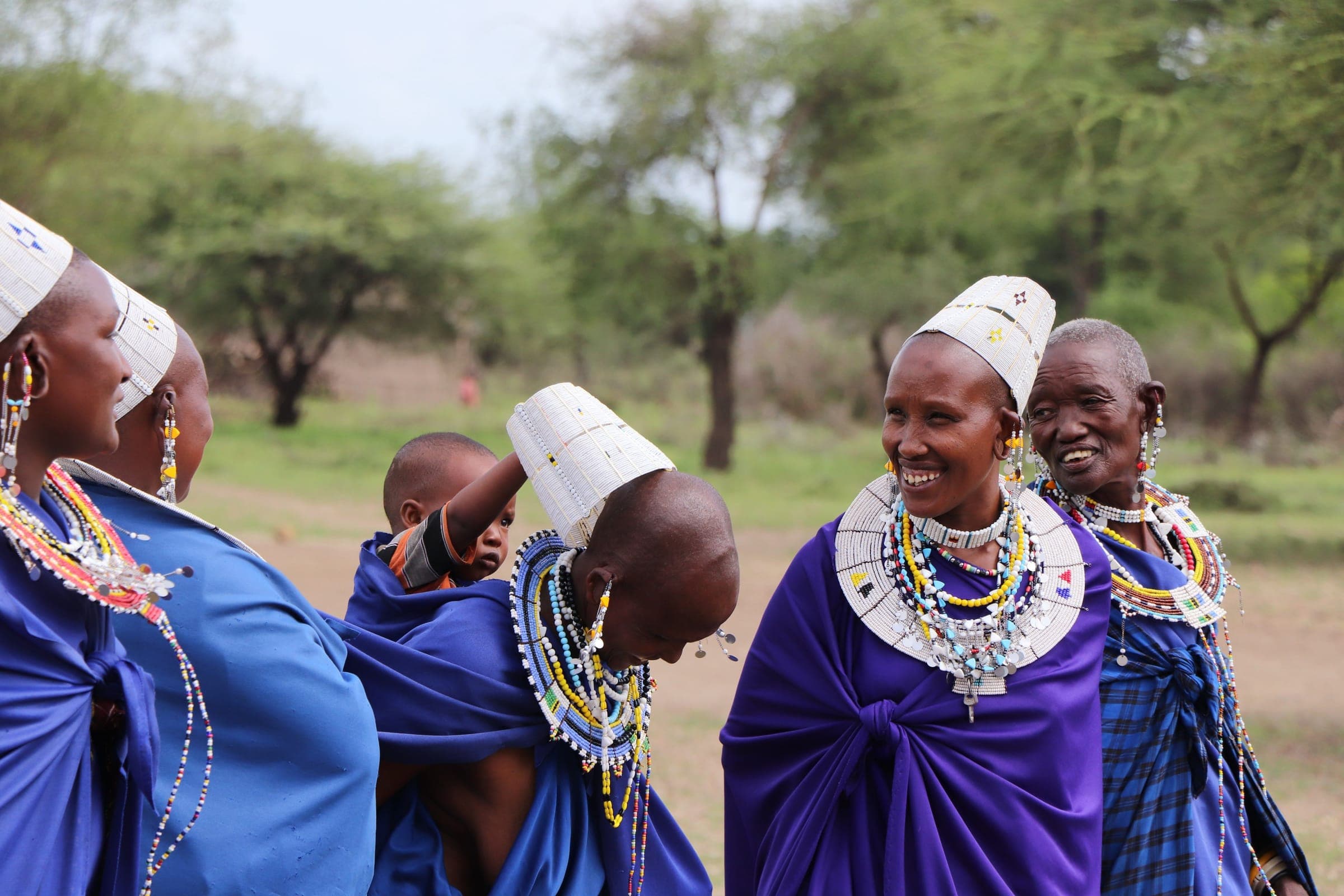 Maasai women in beaded collars and headpieces laughing together