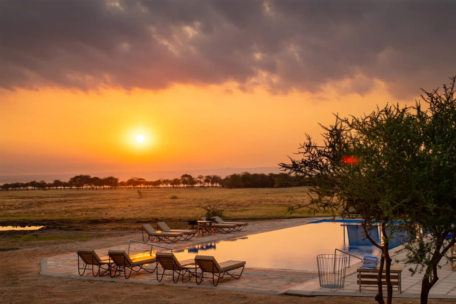 Sunset over the plains beyond the swimming pool and its loungers