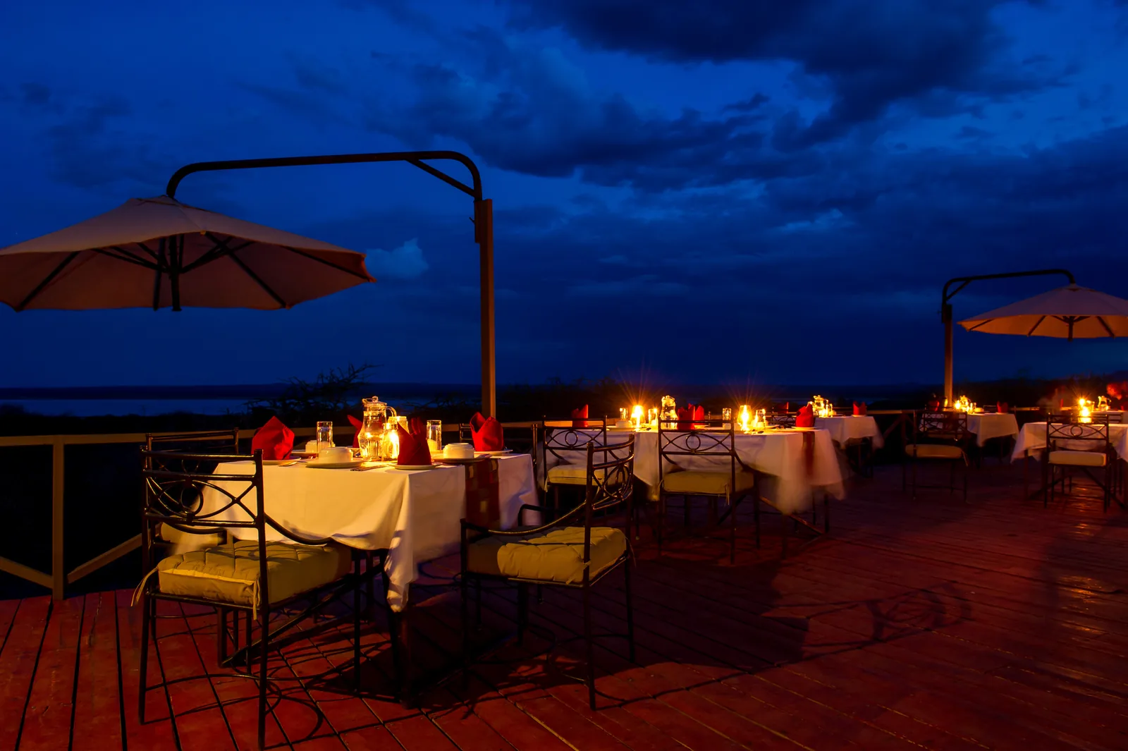 Candlelit dinner tables on the open deck under a deep blue evening sky