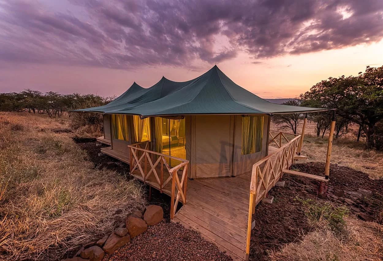 A guest tent on a raised wooden deck at dusk, under a purple sky