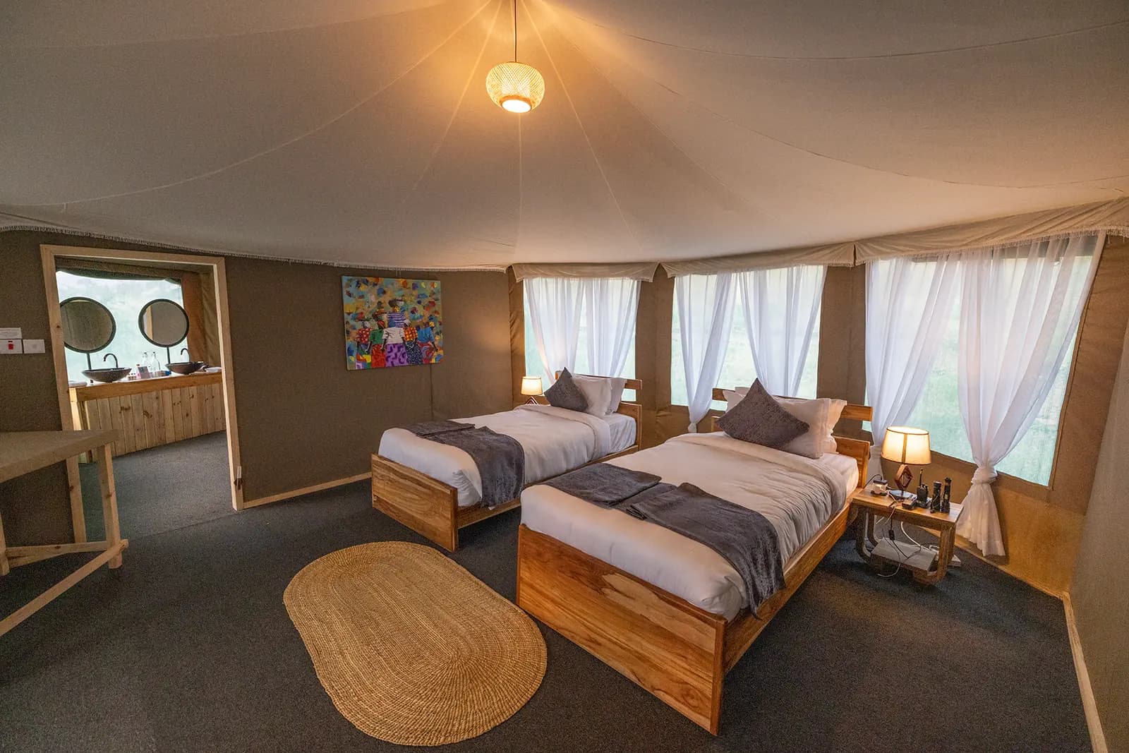 Twin beds in a tent, with the en-suite bathroom behind