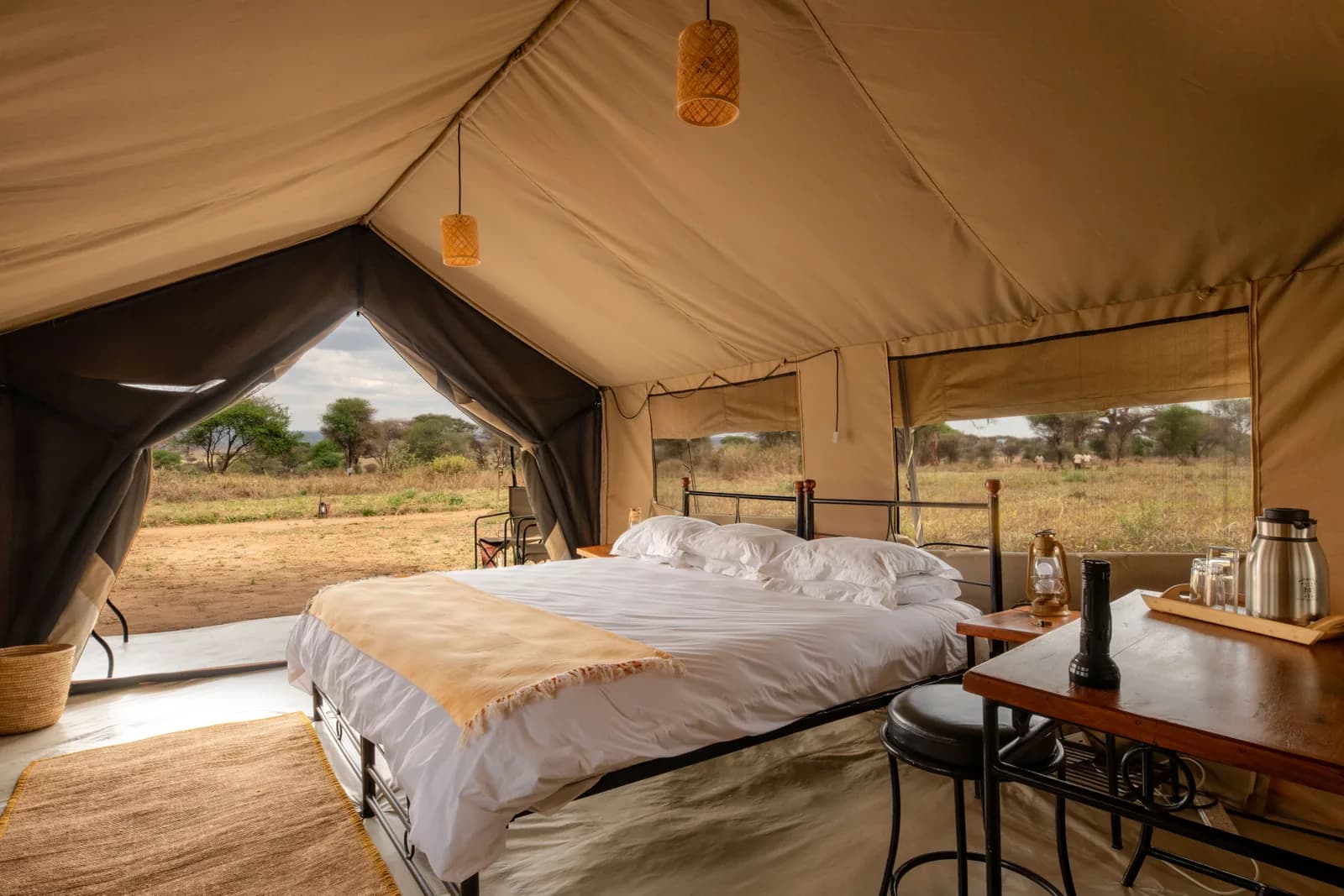 Double bed and a coffee station in a tent, with the bush through the open front