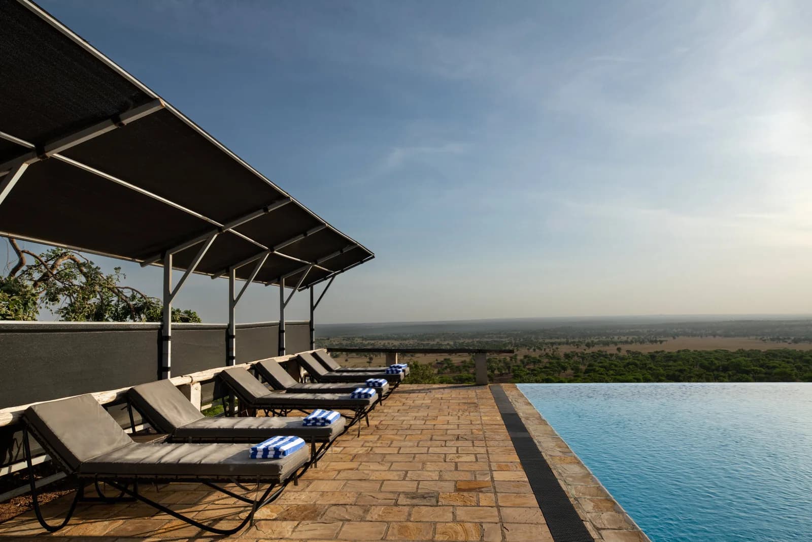 Sun loungers along an infinity pool overlooking the plains at Kubu Kubu Tented Lodge
