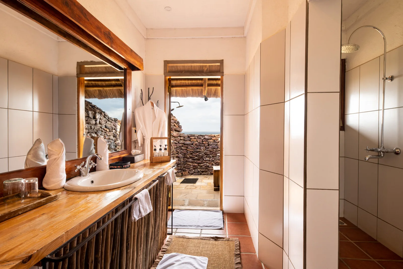 Bathroom with a wooden vanity, walk-in shower and a view through the open door