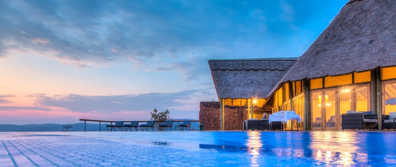The pool and thatched main lodge lit up at dusk