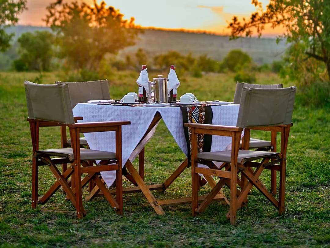 A dinner table set for two on the grass at sunset