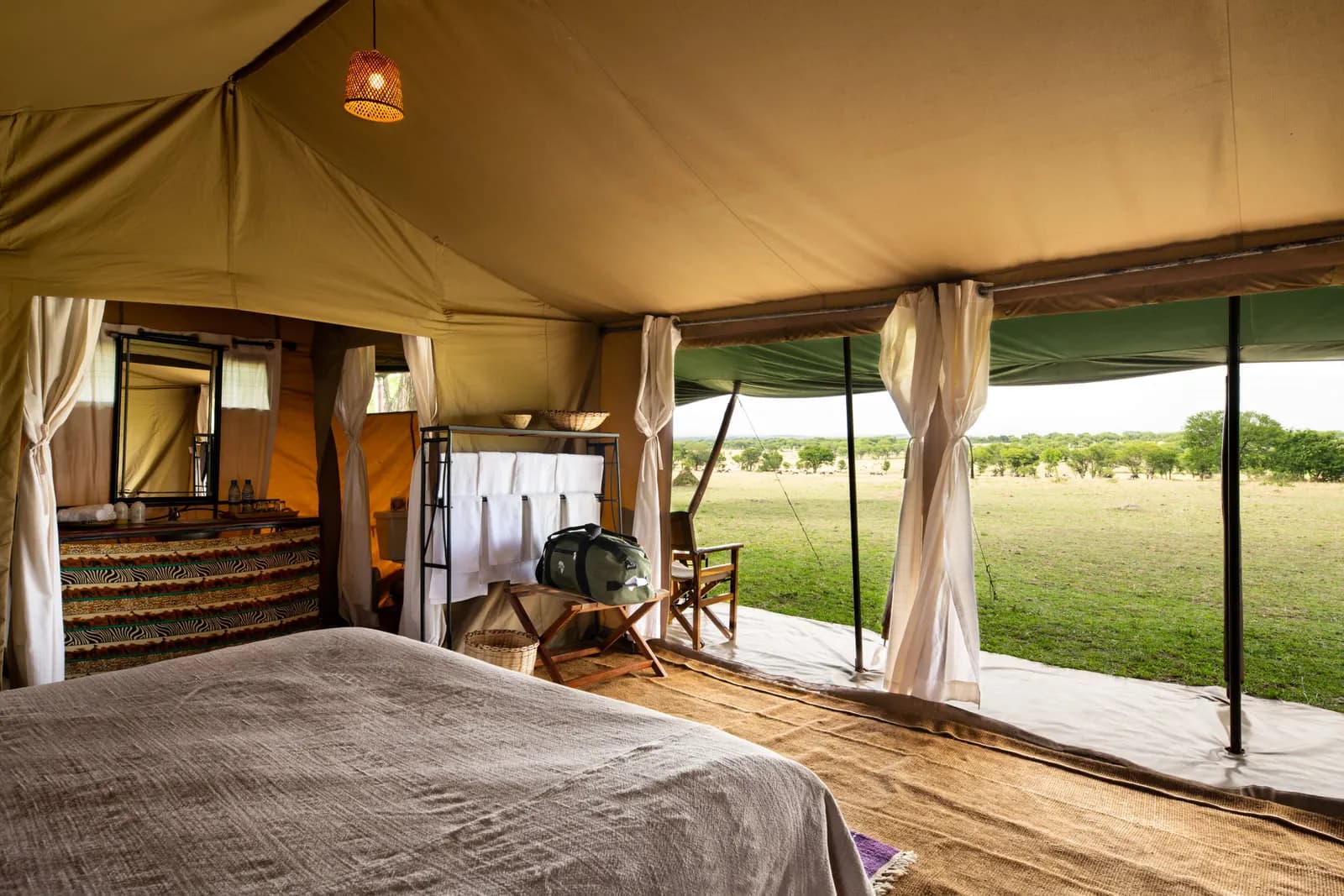 Inside a tent: the bed and a view through the open front onto the plains