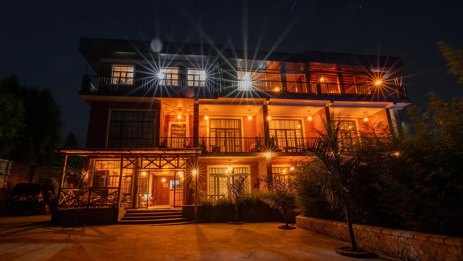 The three-storey red-brick house lit up at night, with balconies on every floor