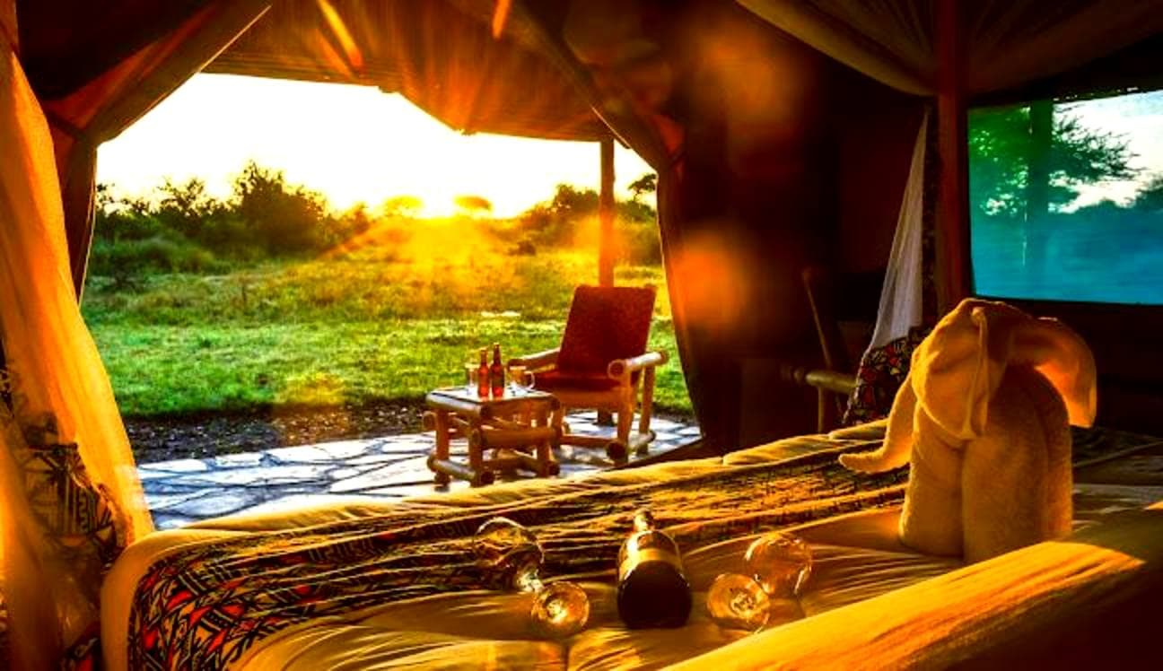 Premium tented camp lit at dusk in remote Tanzanian wilderness