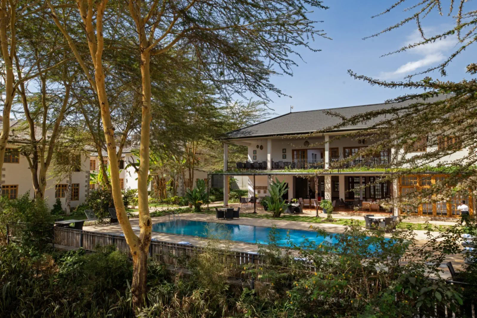 The two-storey house and its swimming pool among acacia trees