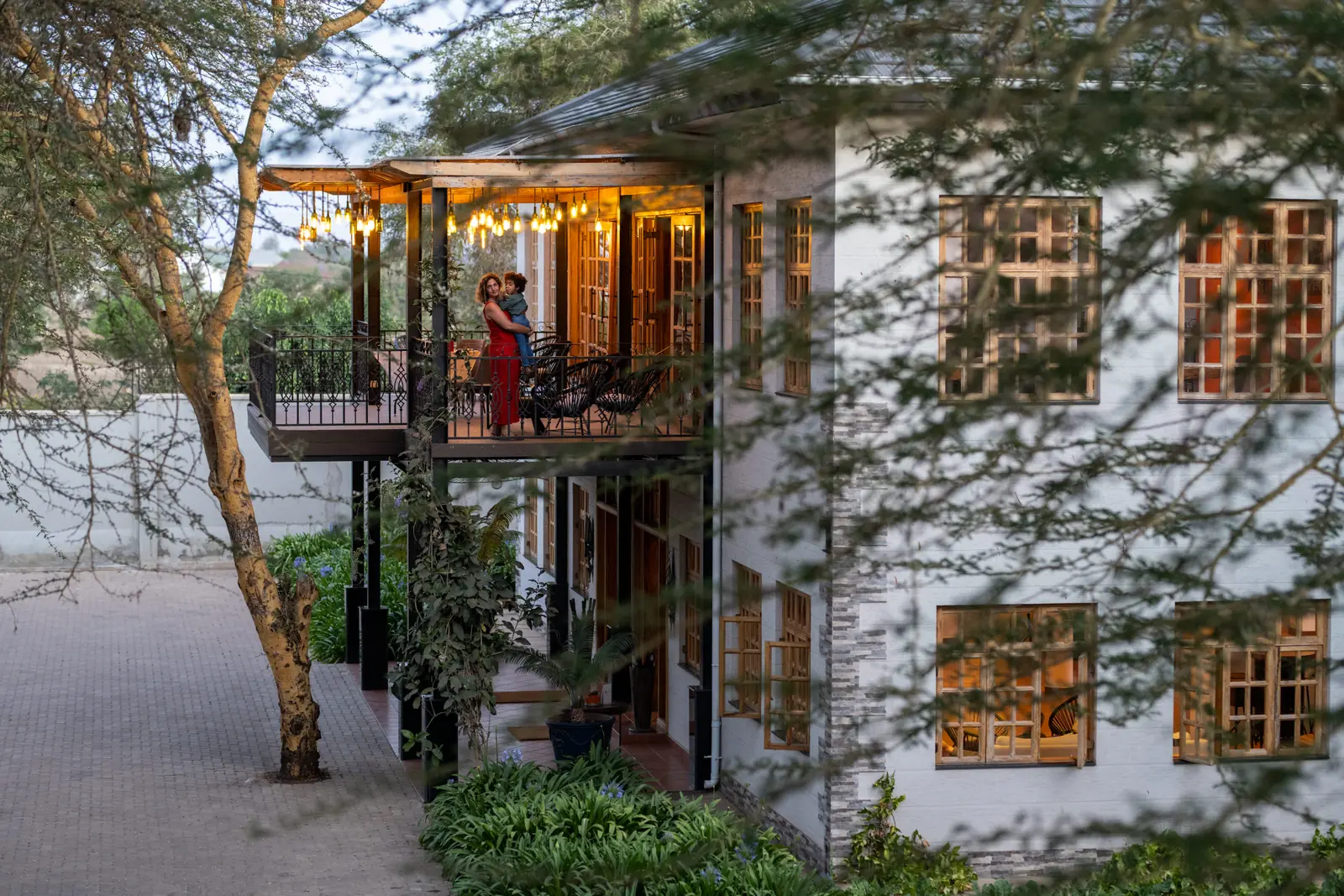 Lit balcony on the white house, seen through acacia branches