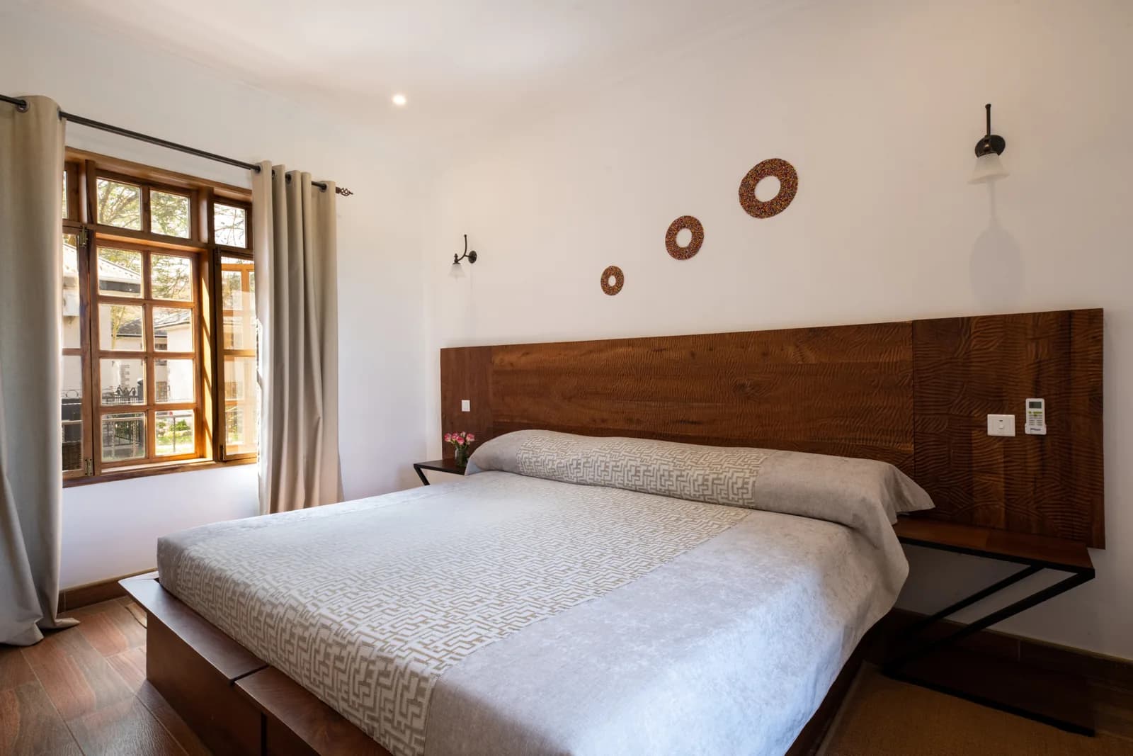 Bedroom with a king-size bed, a timber headboard and tall wooden windows