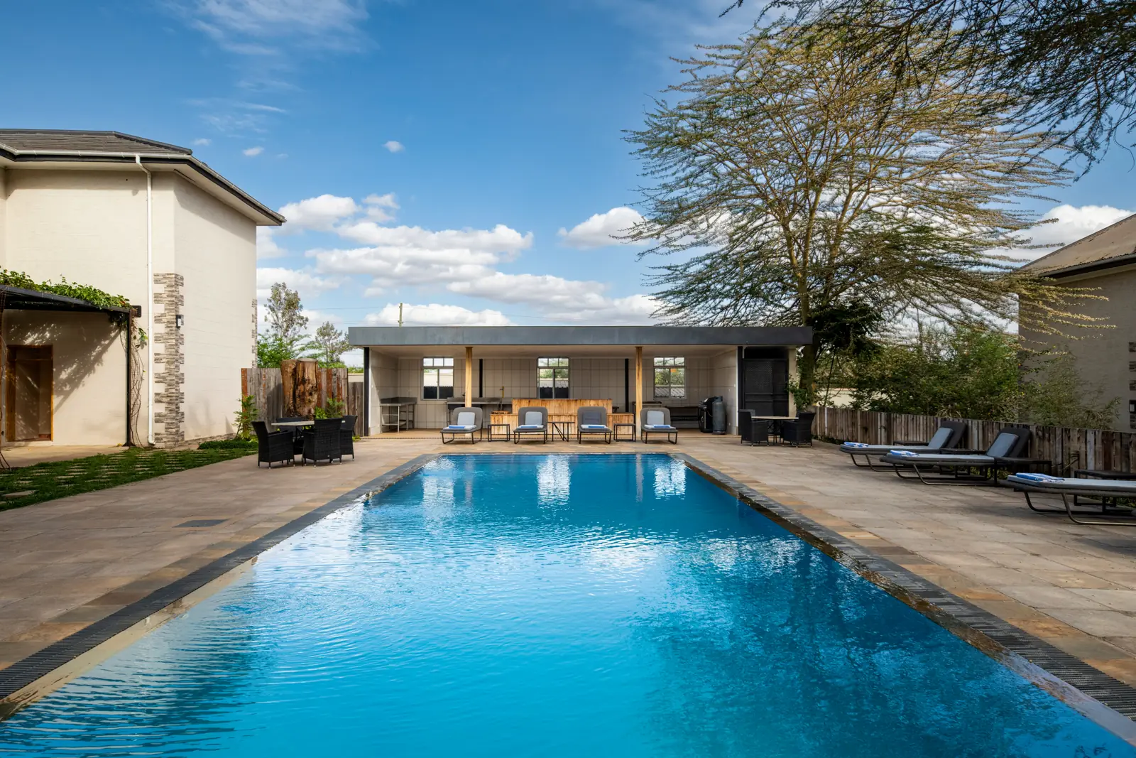 Long swimming pool with loungers, the pool house beyond