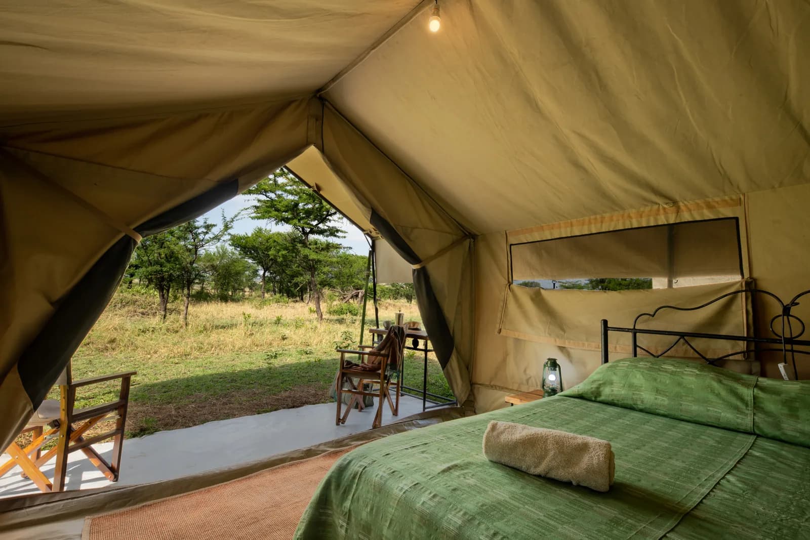 Inside a tent: a double bed, with the plains through the open door