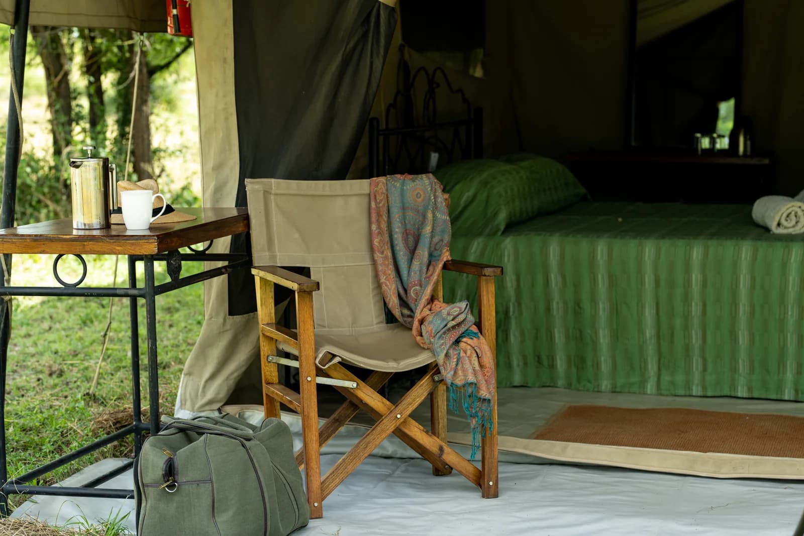 Tent veranda with a camp chair and a coffee table, the bed inside