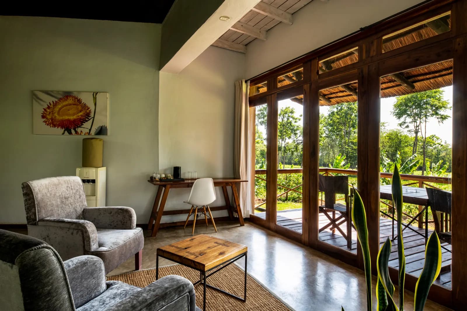 Sitting area with armchairs and a desk by glass doors onto a balcony