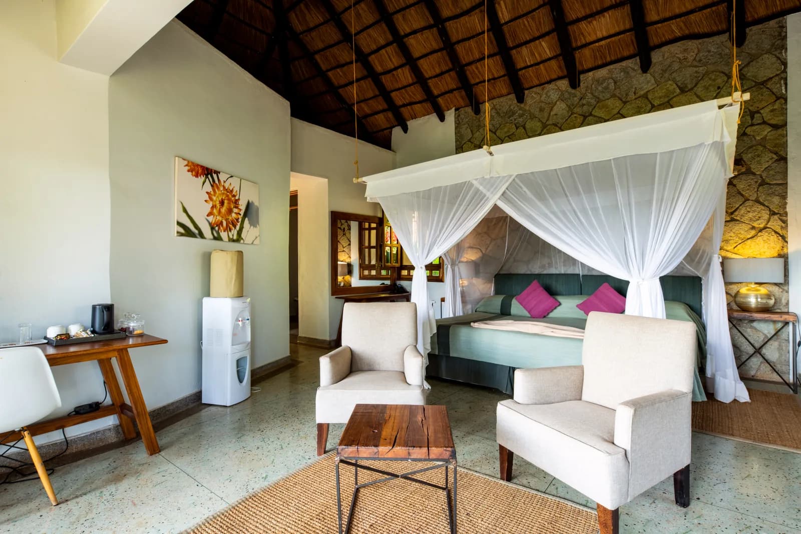 Room with a netted four-poster bed, armchairs and a coffee table