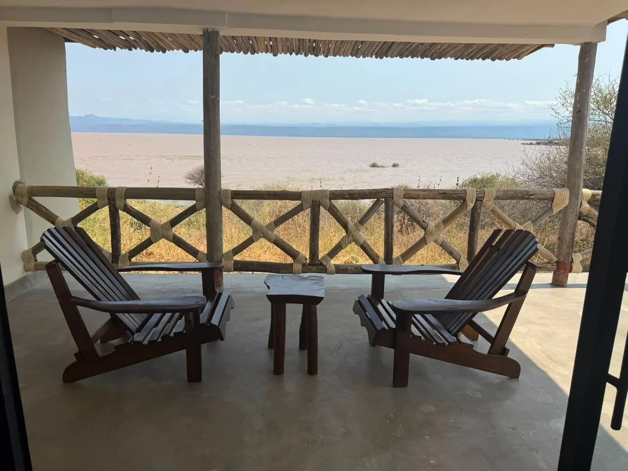 Two wooden armchairs on a covered veranda looking out over Lake Manyara