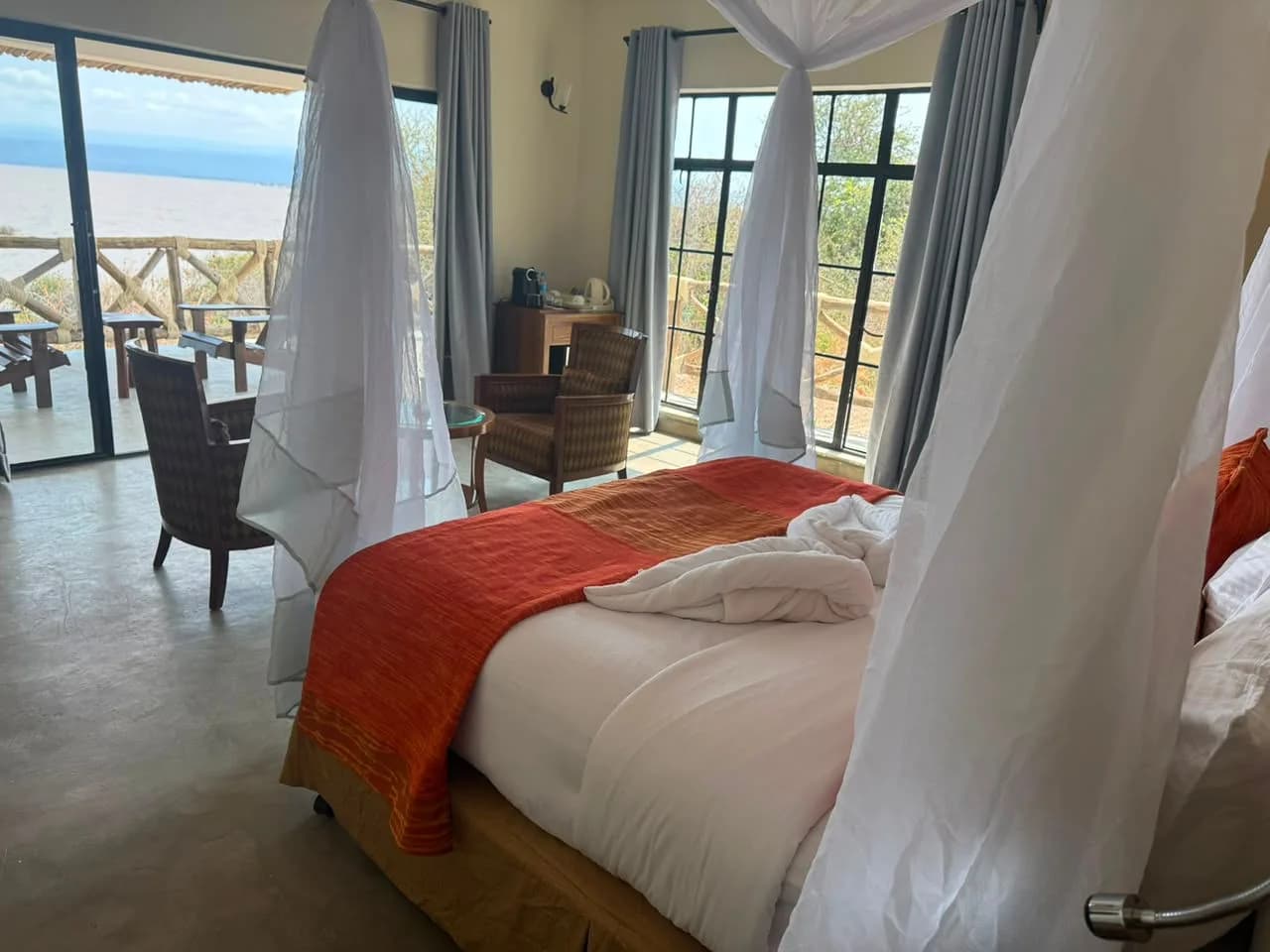 Bedroom with a netted double bed and glass doors onto a veranda over the lake