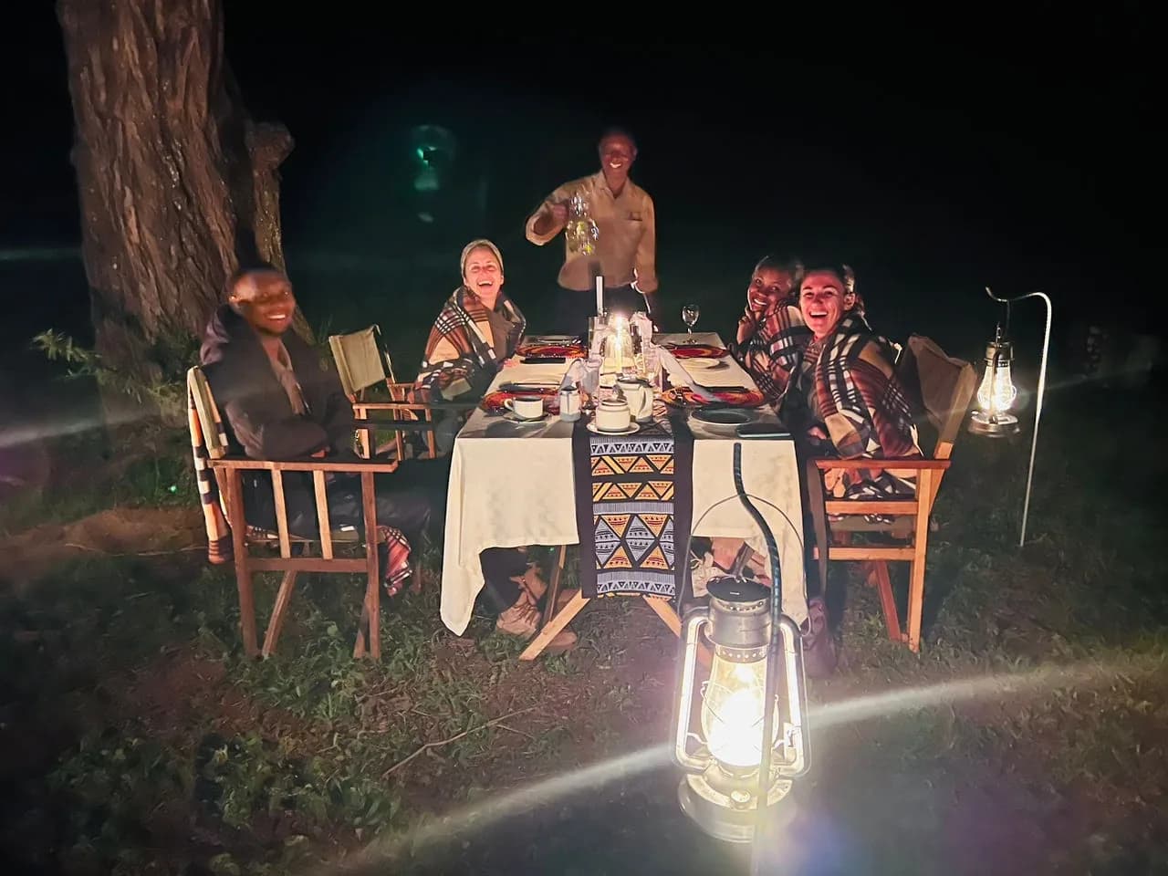Guests at a lantern-lit dinner table at night