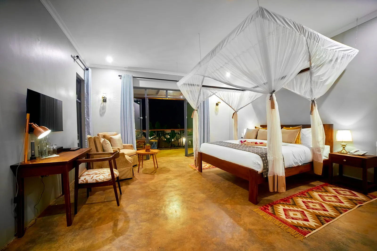 Bedroom with a netted four-poster bed, a desk and a patterned rug