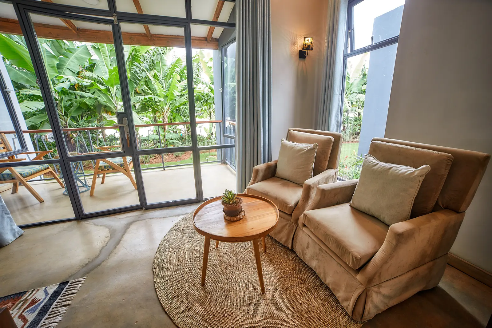 Sitting area with armchairs by glass doors onto a leafy veranda