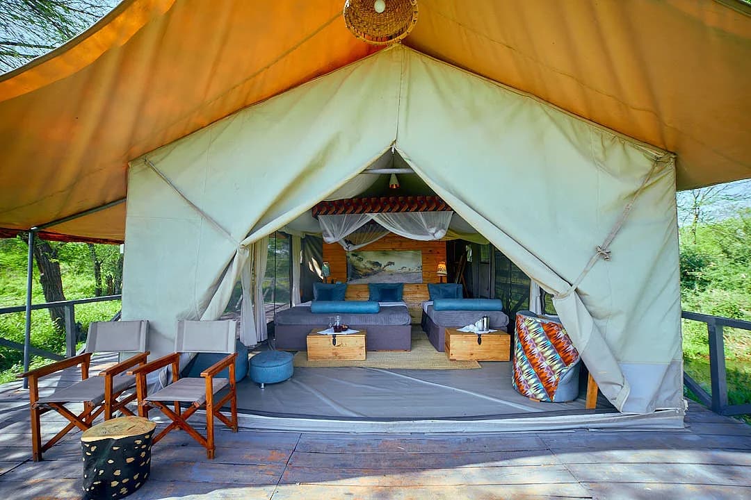 Tent veranda with chairs, and the beds inside through the open front