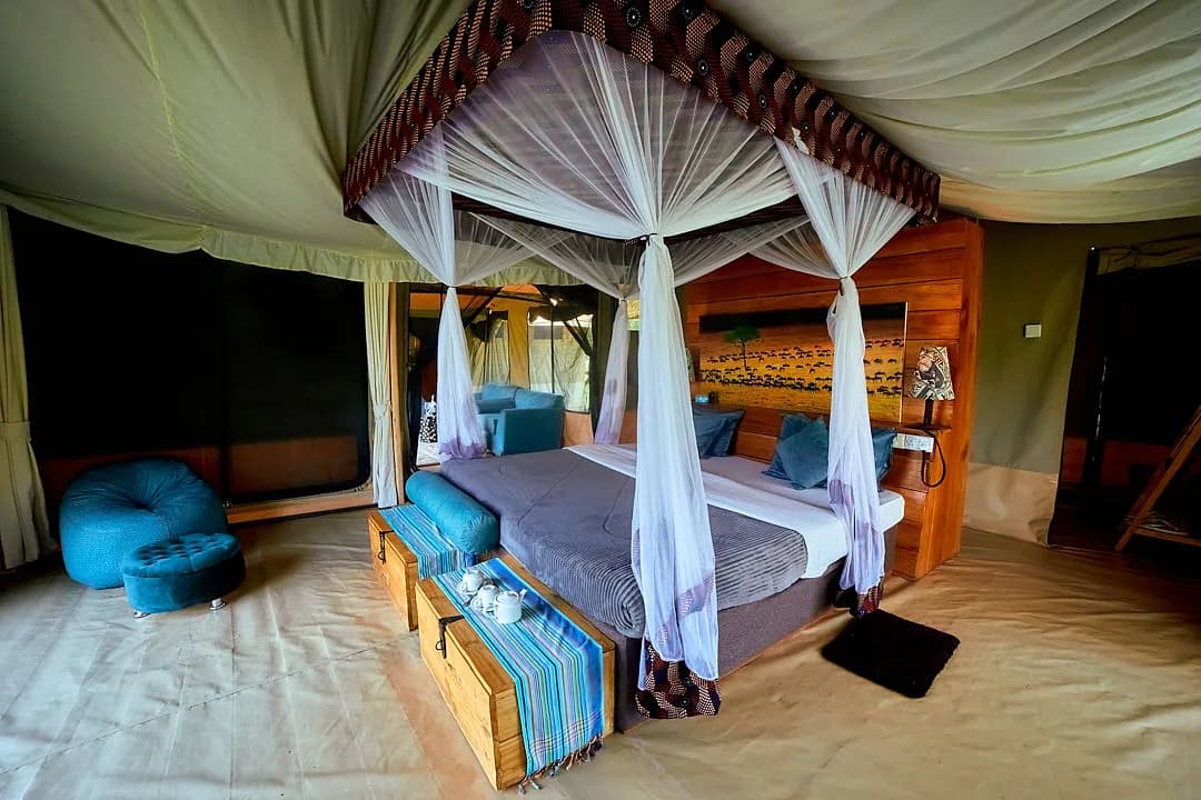 Netted bed in a tent with a carved wooden headboard