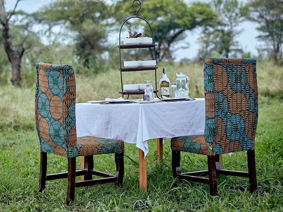 Table for two set for afternoon tea on the grass among acacias