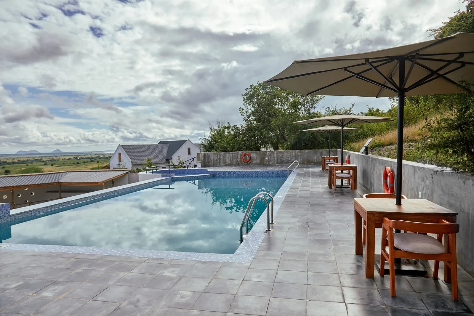 Swimming pool and parasol-shaded tables on a hillside terrace