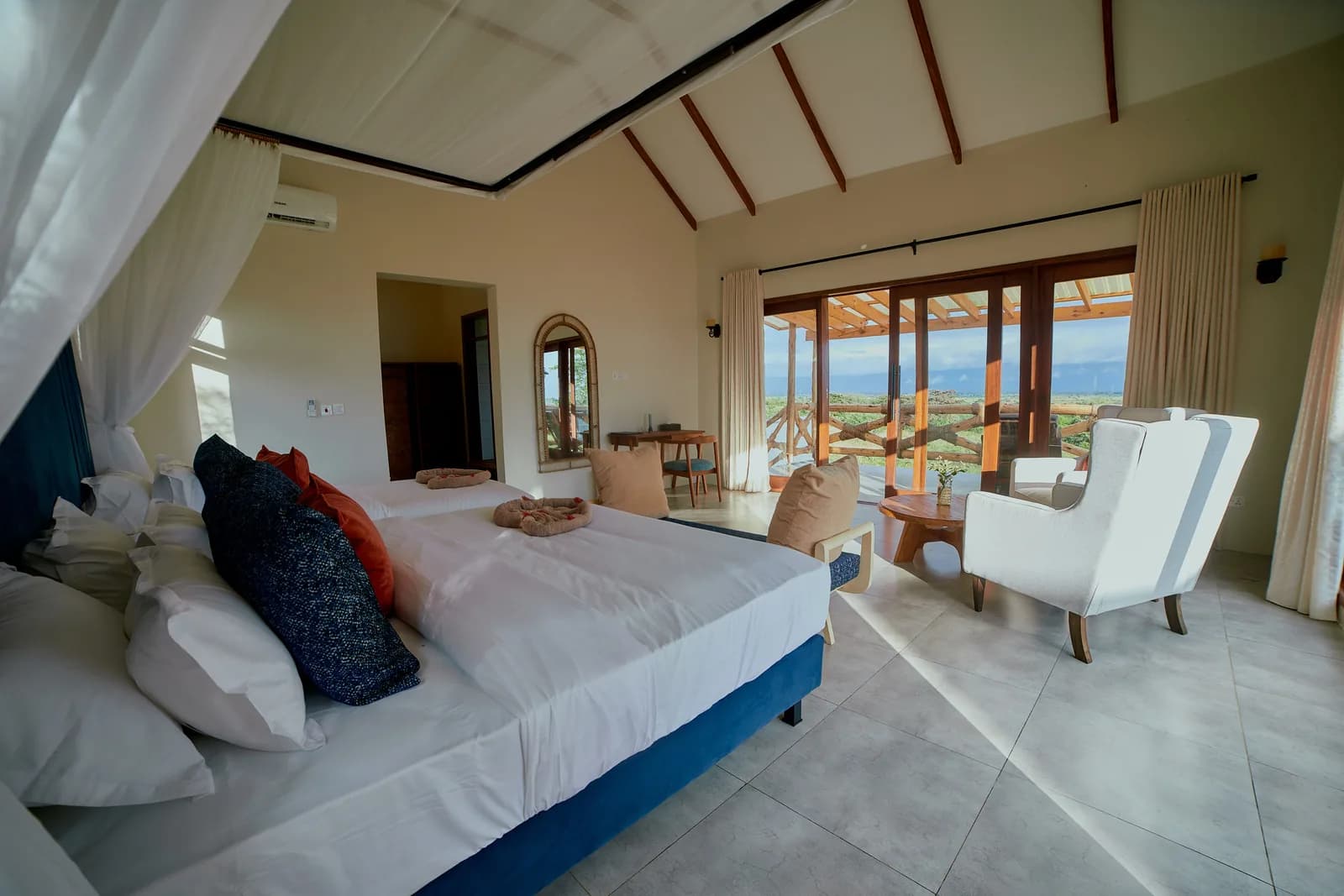Bedroom with a double bed, armchairs and glass doors to a terrace