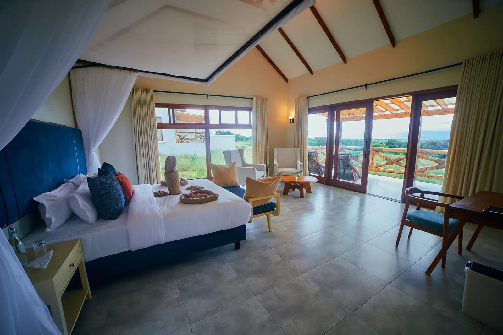 Bedroom with a netted bed and a sitting area by tall glass doors
